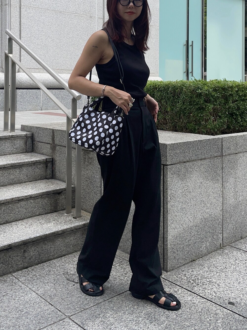 ブラック系のサンダル、ブラック系のパンツ、ホワイト系のタンクトップを着用したレディースの夏コーディネートの2枚目の写真