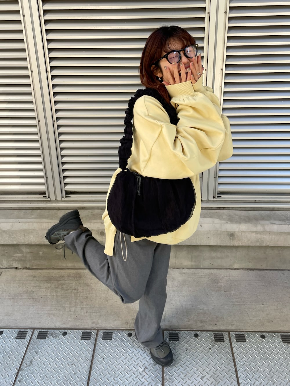 ブラック系のショルダーバッグ、イエロー系のスウェット、グレー系のパンツを着用したレディースの冬コーディネートの4枚目の写真