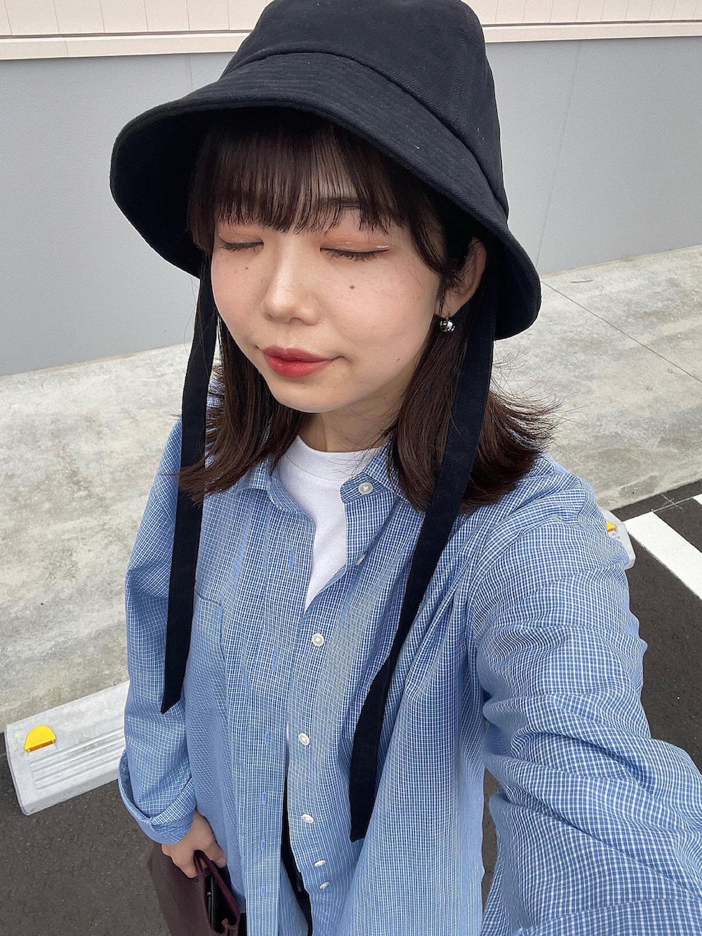 ブラウン系のハンドバッグ、ホワイト系のスニーカー、ブラック系のハットを着用したレディースの春コーディネートの4枚目の写真