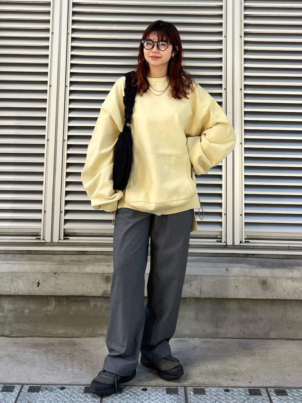 ブラック系のショルダーバッグ、イエロー系のスウェット、グレー系のパンツを着用したレディースの冬コーディネートの3枚目の写真