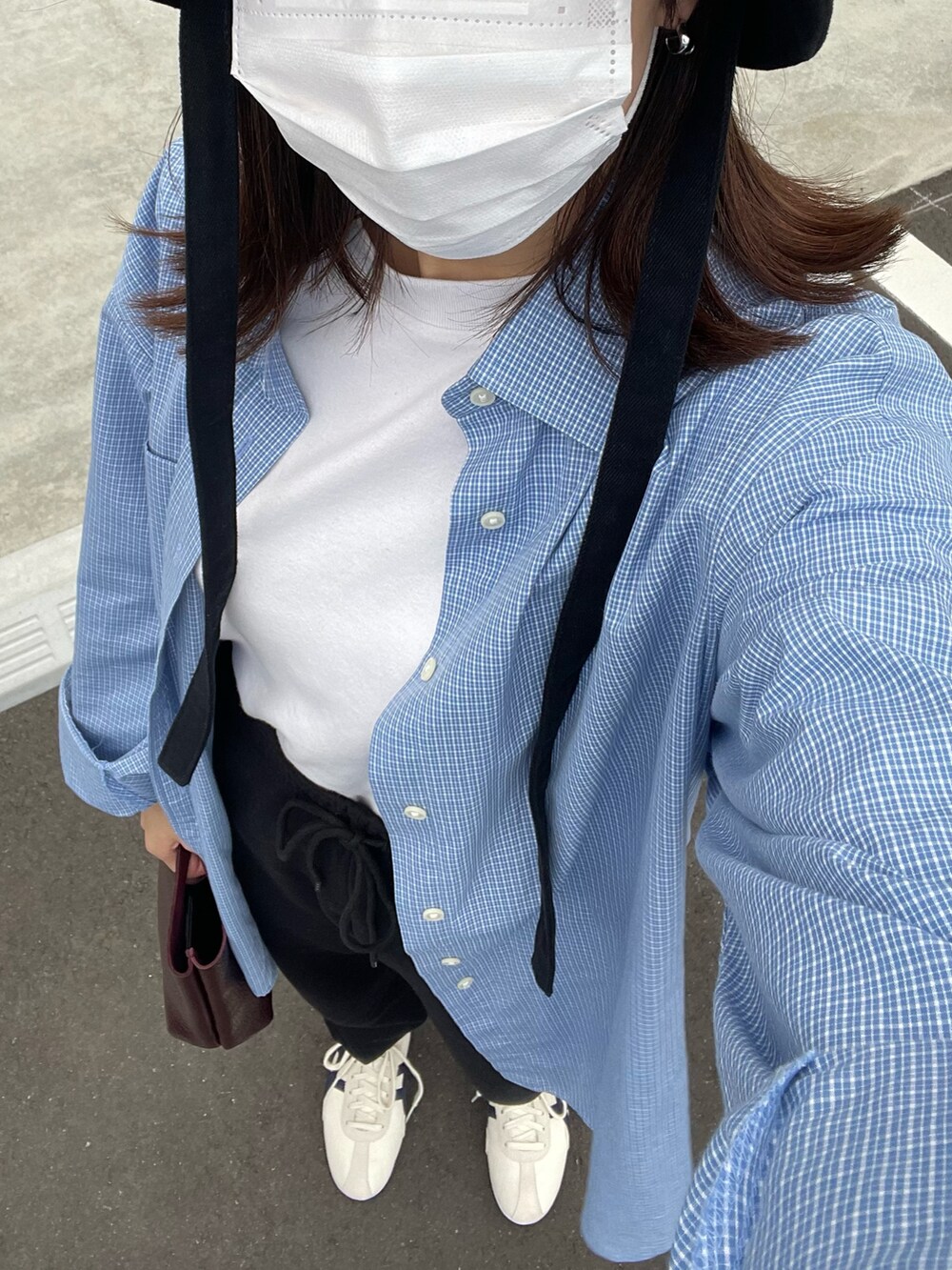 ブラウン系のハンドバッグ、ホワイト系のスニーカー、ブラック系のハットを着用したレディースの春コーディネートの2枚目の写真