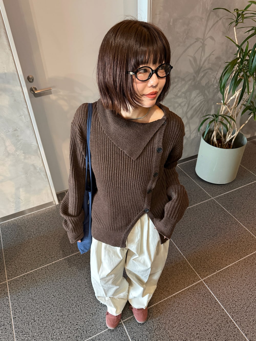 ブラウン系のニット/セーター、ホワイト系のスラックス、ブルー系のショルダーバッグを着用したレディースの冬コーディネートの4枚目の写真