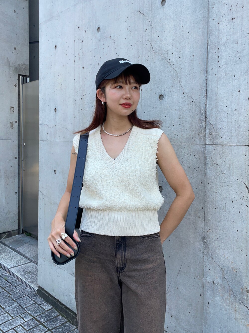 ホワイト系のベスト、ブラック系のショルダーバッグ、ブラウン系のデニムパンツを着用したレディースの夏コーディネートの3枚目の写真