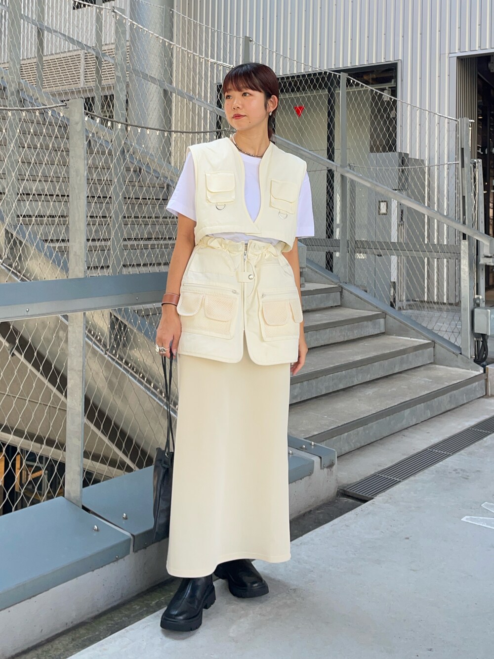 ホワイト系のベスト、ホワイト系のスカート、ブラック系のブーツを着用したレディースの秋コーディネートの2枚目の写真