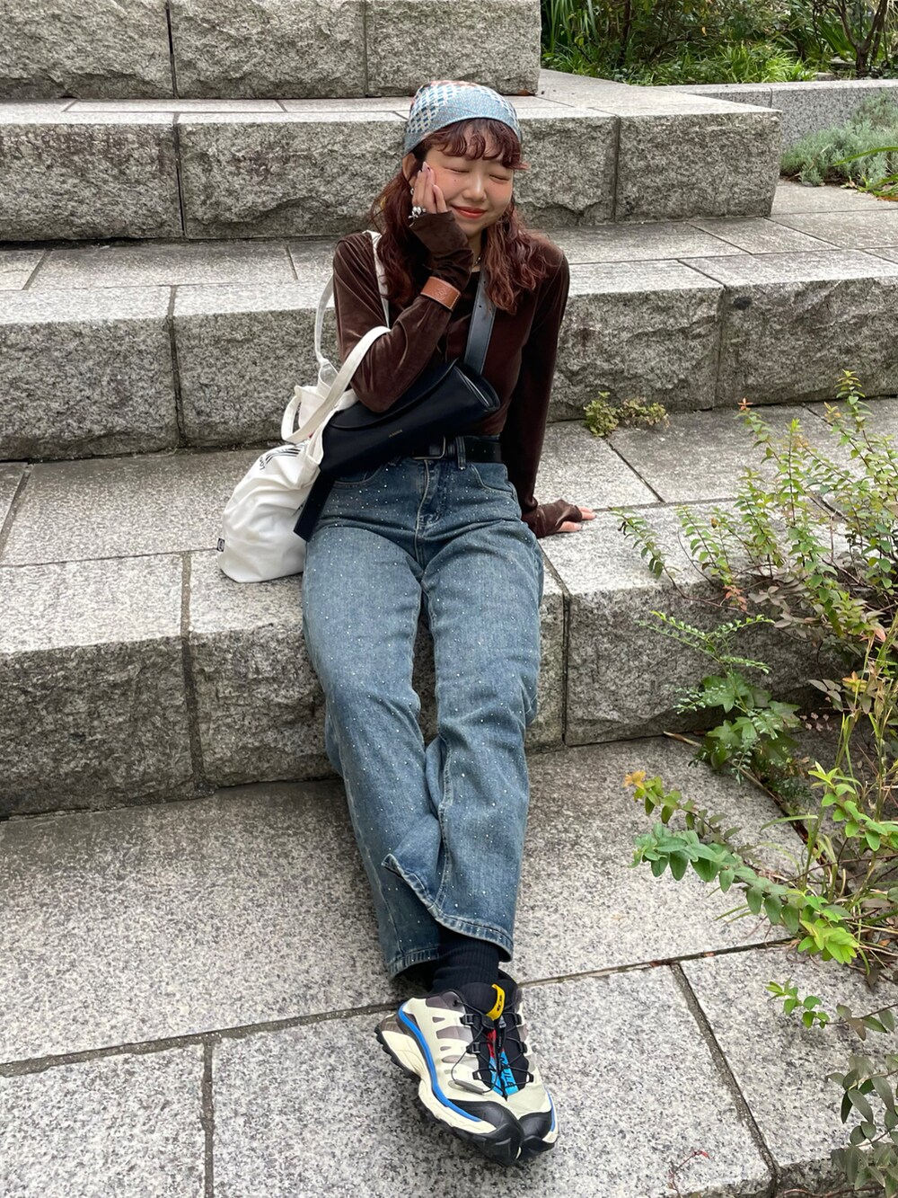 ブラウン系のTシャツ/カットソー、ブラック系のショルダーバッグ、ブルー系のデニムパンツを着用したレディースの秋コーディネートの2枚目の写真