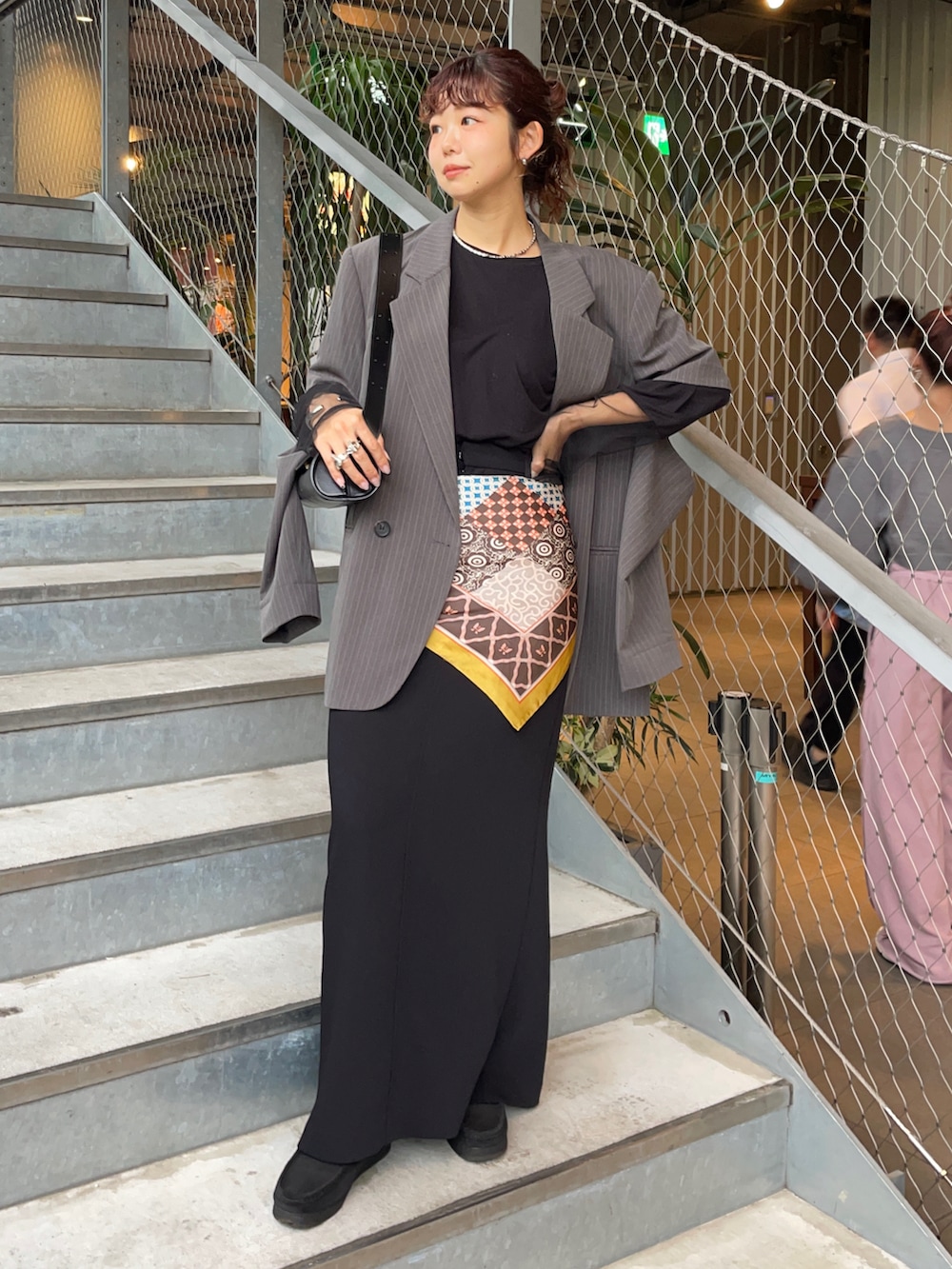 グレー系のテーラードジャケット、ブラック系のスカート、ブラック系のブーツを着用したレディースの秋コーディネートの2枚目の写真