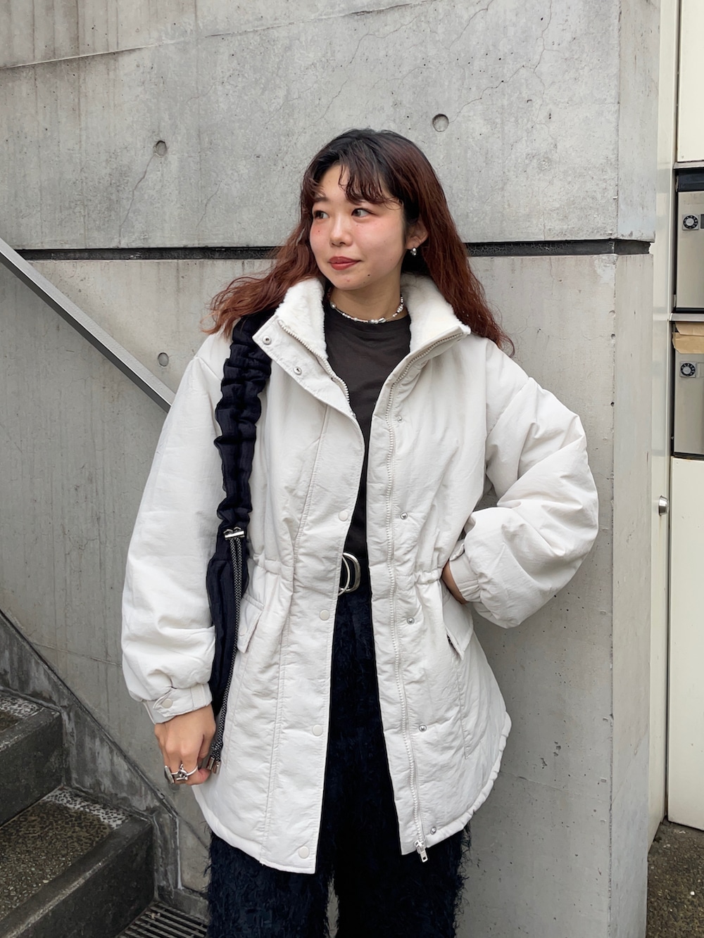 ブラック系のショルダーバッグ、ホワイト系のブルゾン、グレー系のTシャツ/カットソーを着用したレディースの冬コーディネートの2枚目の写真