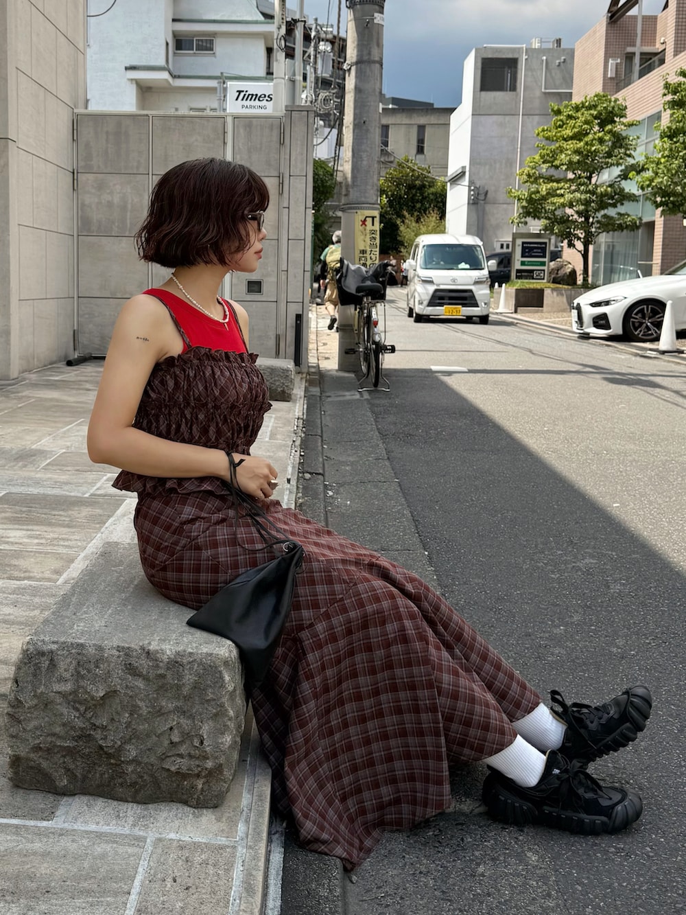 ブラウン系のワンピース、ブラック系のショルダーバッグ、レッド系のタンクトップを着用したレディースの夏コーディネートの3枚目の写真