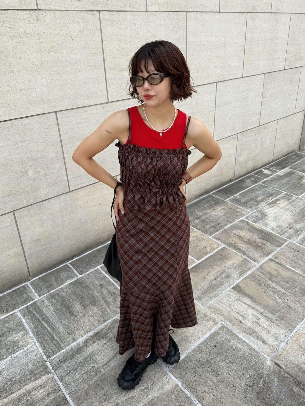 ブラウン系のワンピース、ブラック系のショルダーバッグ、レッド系のタンクトップを着用したレディースの夏コーディネートの4枚目の写真