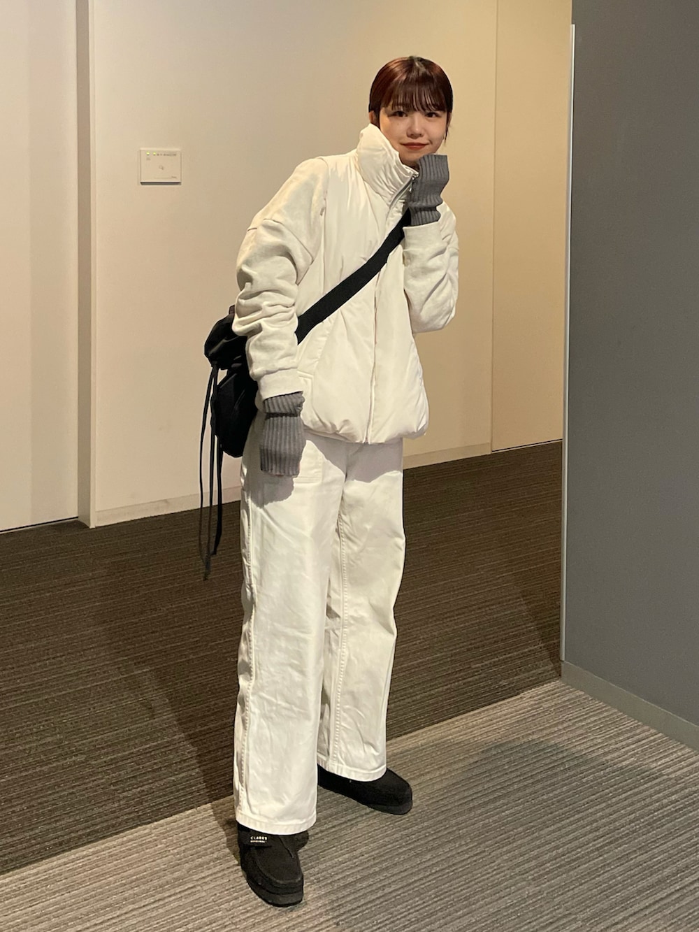 ホワイト系のダウンベスト、ホワイト系のその他パンツ、ブラック系のブーツを着用したレディースの秋コーディネートの2枚目の写真