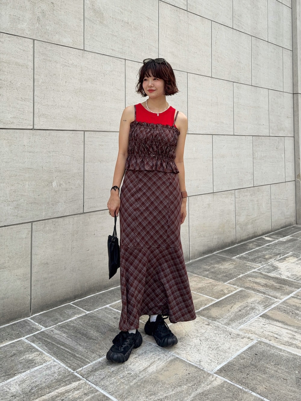 ブラウン系のワンピース、ブラック系のショルダーバッグ、レッド系のタンクトップを着用したレディースの夏コーディネートの2枚目の写真