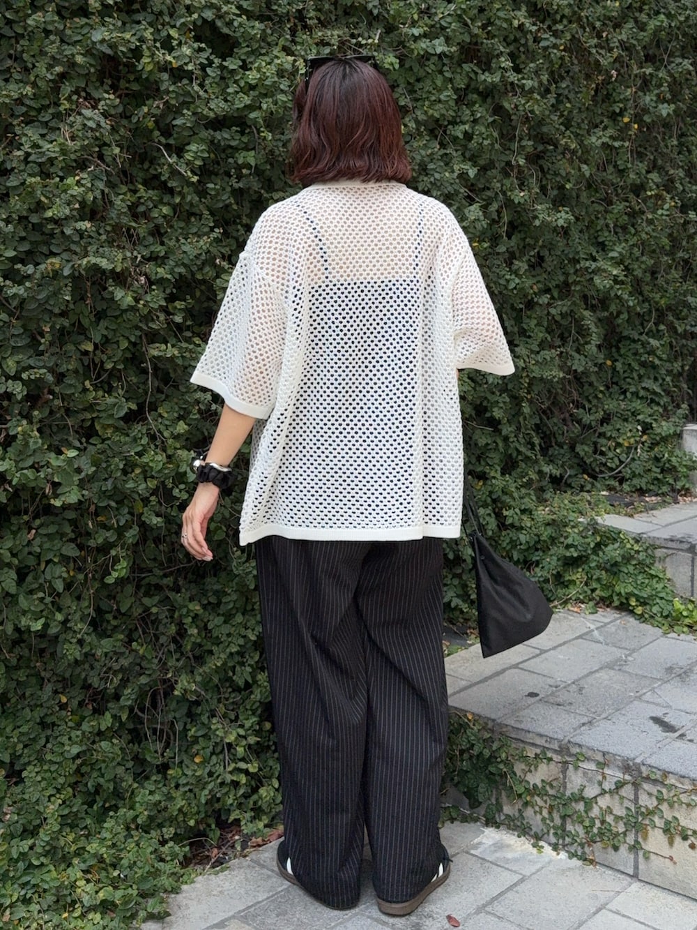 ブラック系のスラックス、ホワイト系のシャツ/ブラウス、ブラック系のショルダーバッグを着用したレディースの夏コーディネートの3枚目の写真