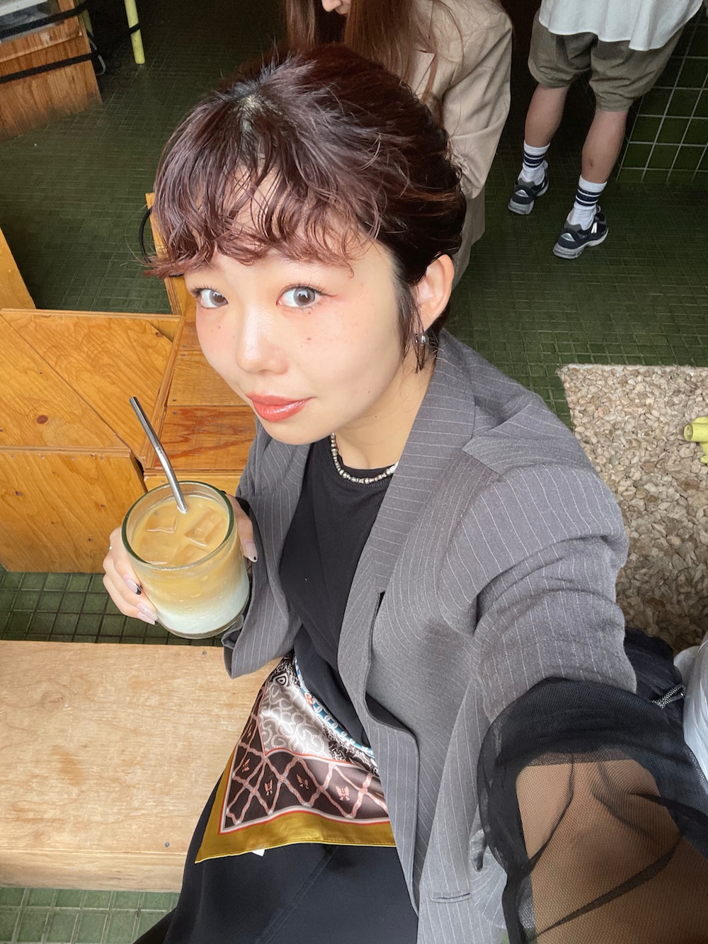 グレー系のテーラードジャケット、ブラック系のスカート、ブラック系のブーツを着用したレディースの秋コーディネートの4枚目の写真