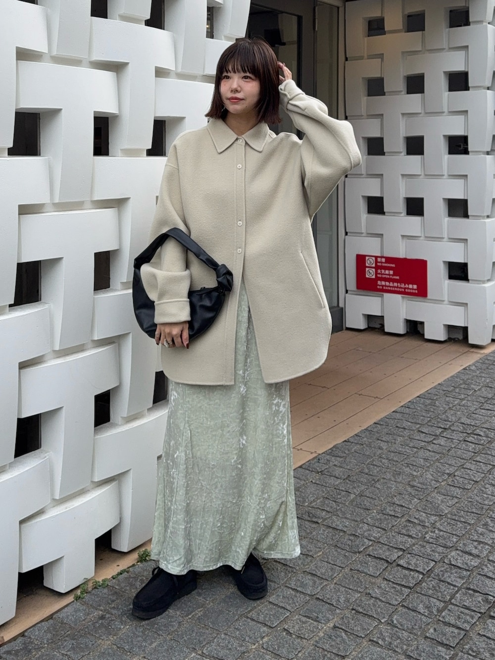 グリーン系のテーラードジャケット、ホワイト系のスカート、ブラック系のハンドバッグを着用したレディースの冬コーディネートの3枚目の写真