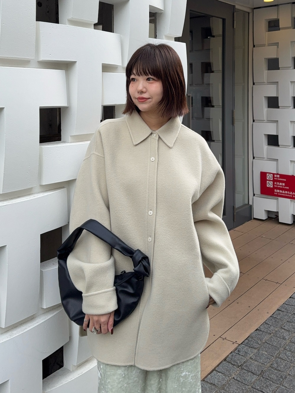 グリーン系のテーラードジャケット、ホワイト系のスカート、ブラック系のハンドバッグを着用したレディースの冬コーディネートの4枚目の写真