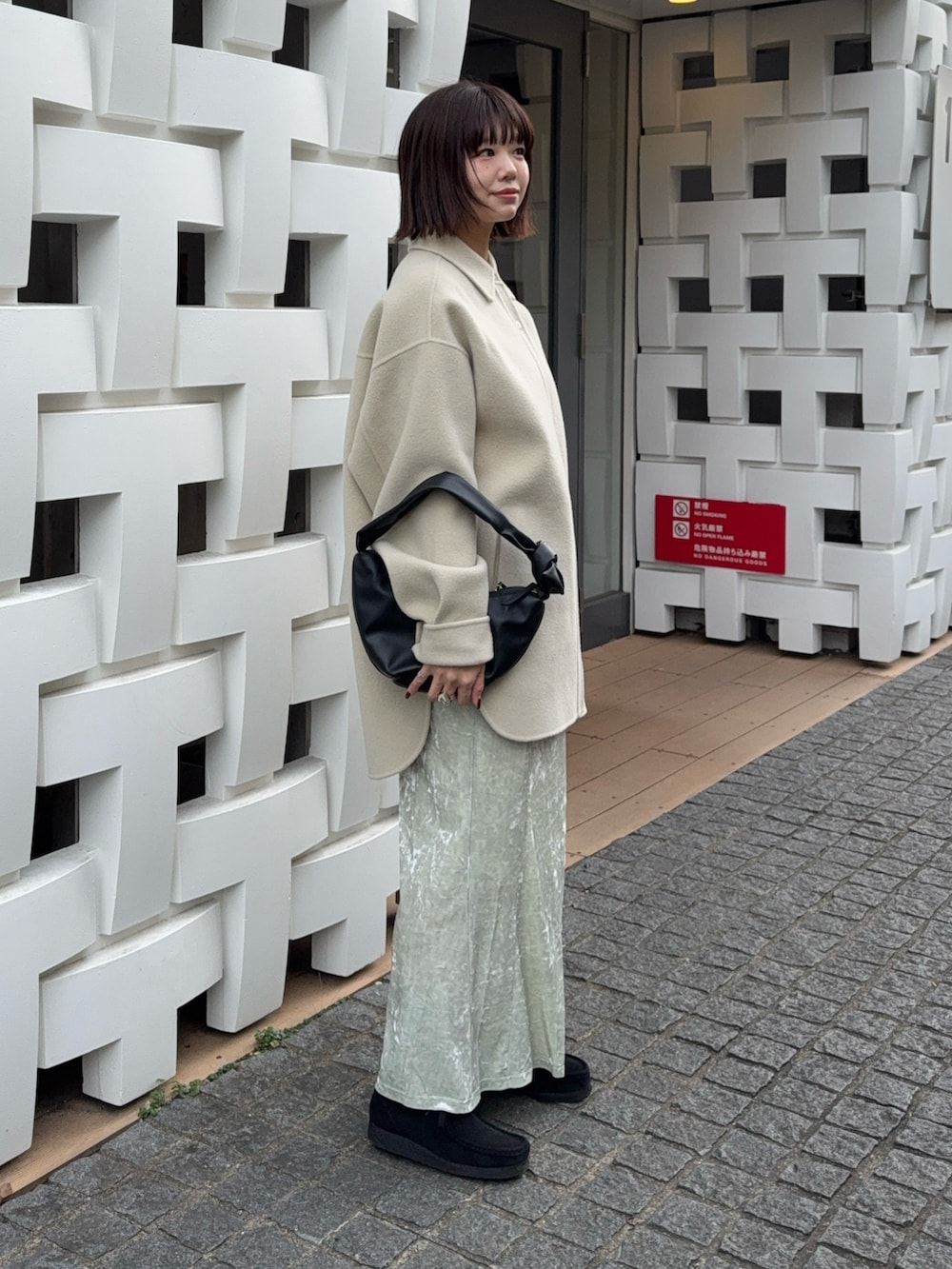 グリーン系のテーラードジャケット、ホワイト系のスカート、ブラック系のハンドバッグを着用したレディースの冬コーディネートの2枚目の写真