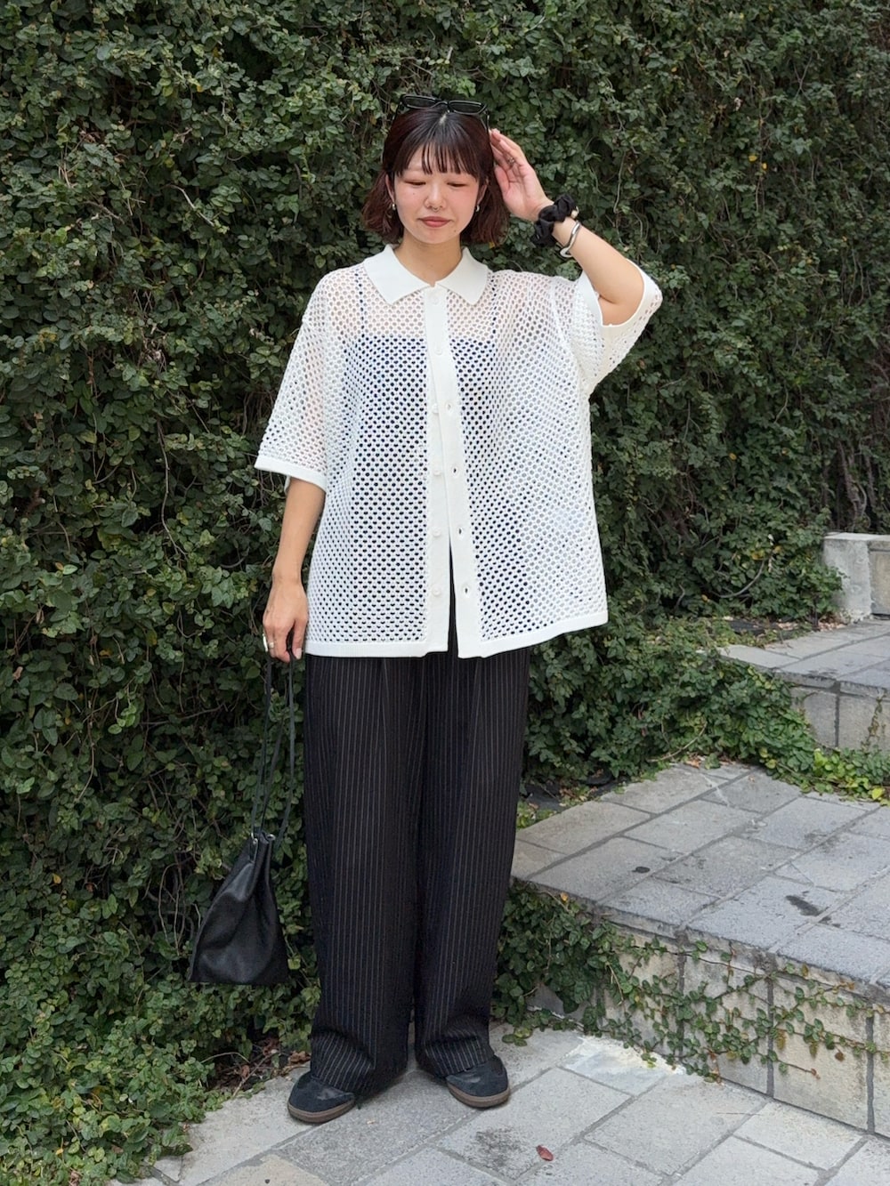 ブラック系のスラックス、ホワイト系のシャツ/ブラウス、ブラック系のショルダーバッグを着用したレディースの夏コーディネートの2枚目の写真