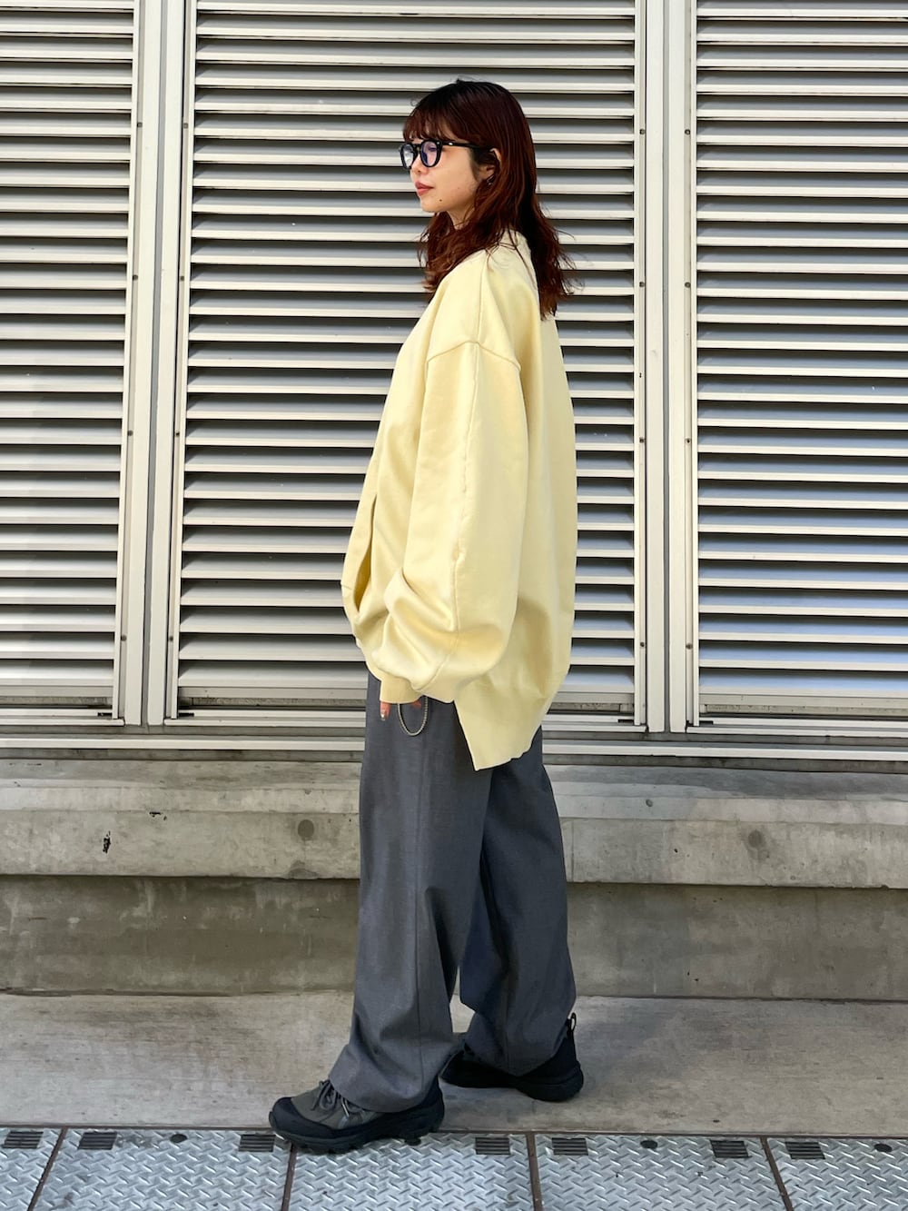 ブラック系のショルダーバッグ、イエロー系のスウェット、グレー系のパンツを着用したレディースの冬コーディネートの2枚目の写真