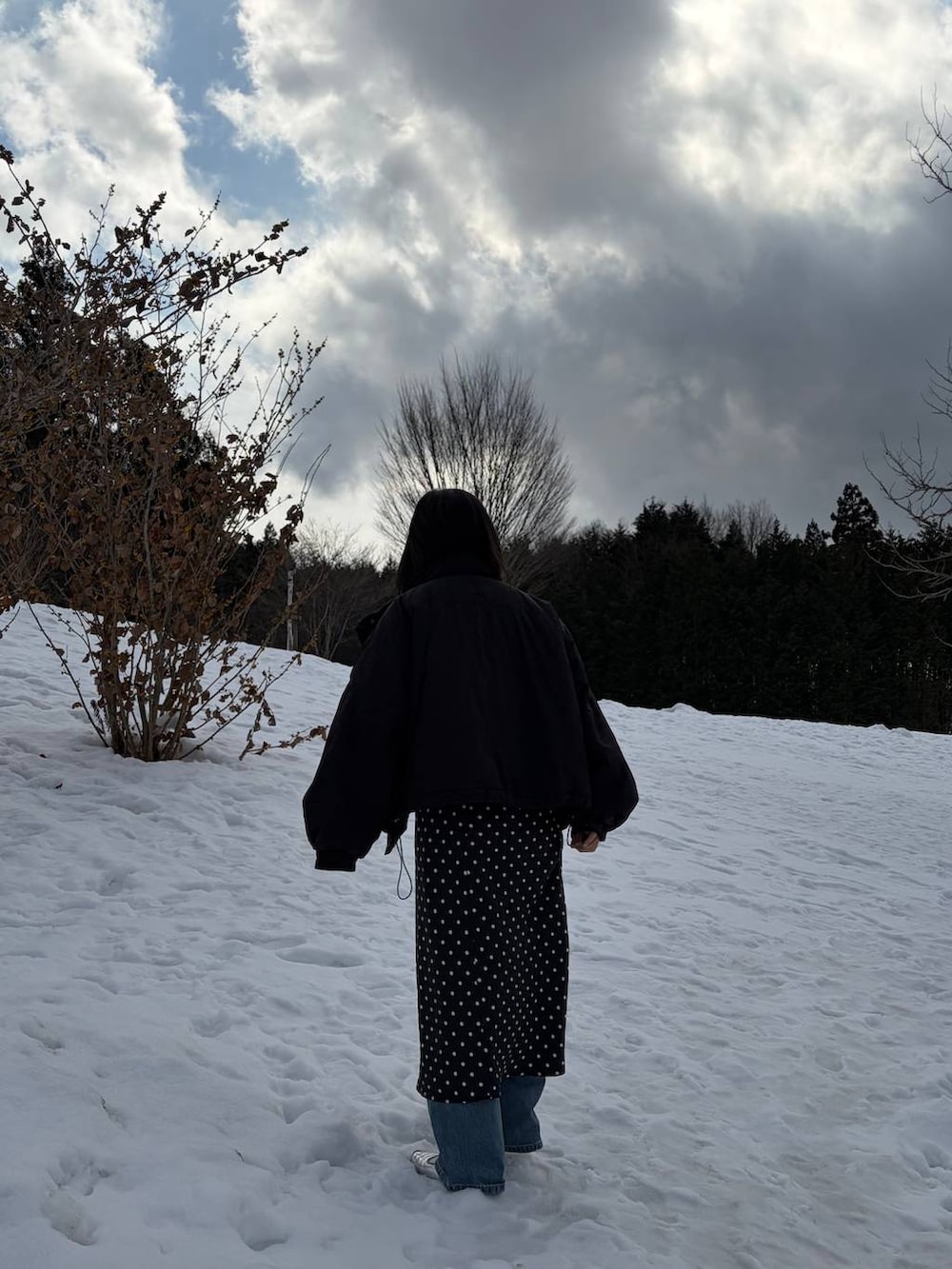 ブラック系のその他アウター、ブラック系のスカート、グレー系のニット/セーターを着用したレディースの冬コーディネートの2枚目の写真