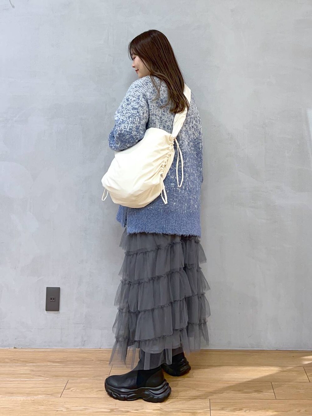 ホワイト系のショルダーバッグ、ブルー系のニット/セーター、グレー系のスカートを着用したレディースの秋コーディネートの3枚目の写真