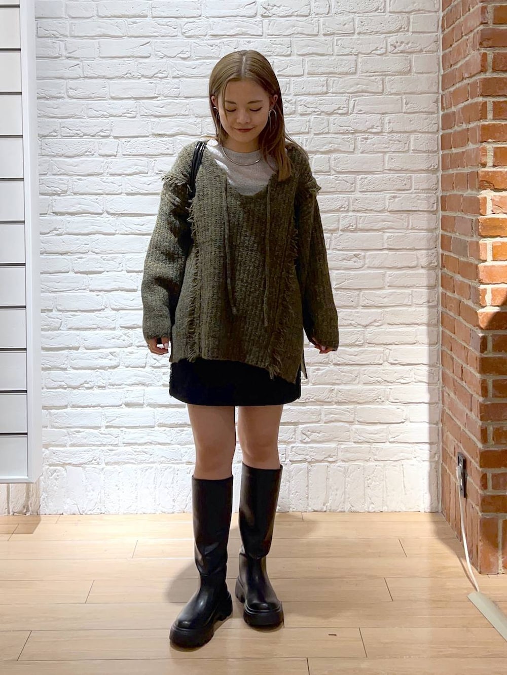 グリーン系のニット/セーター、シルバー系のTシャツ/カットソー、ブラック系のショルダーバッグを着用したレディースの秋コーディネートの2枚目の写真