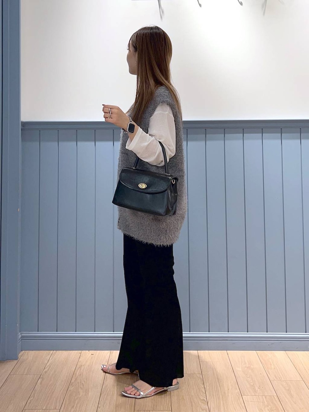 シルバー系のサンダル、ブラック系のボストンバッグ、グレー系のベストを着用したレディースの秋コーディネートの2枚目の写真