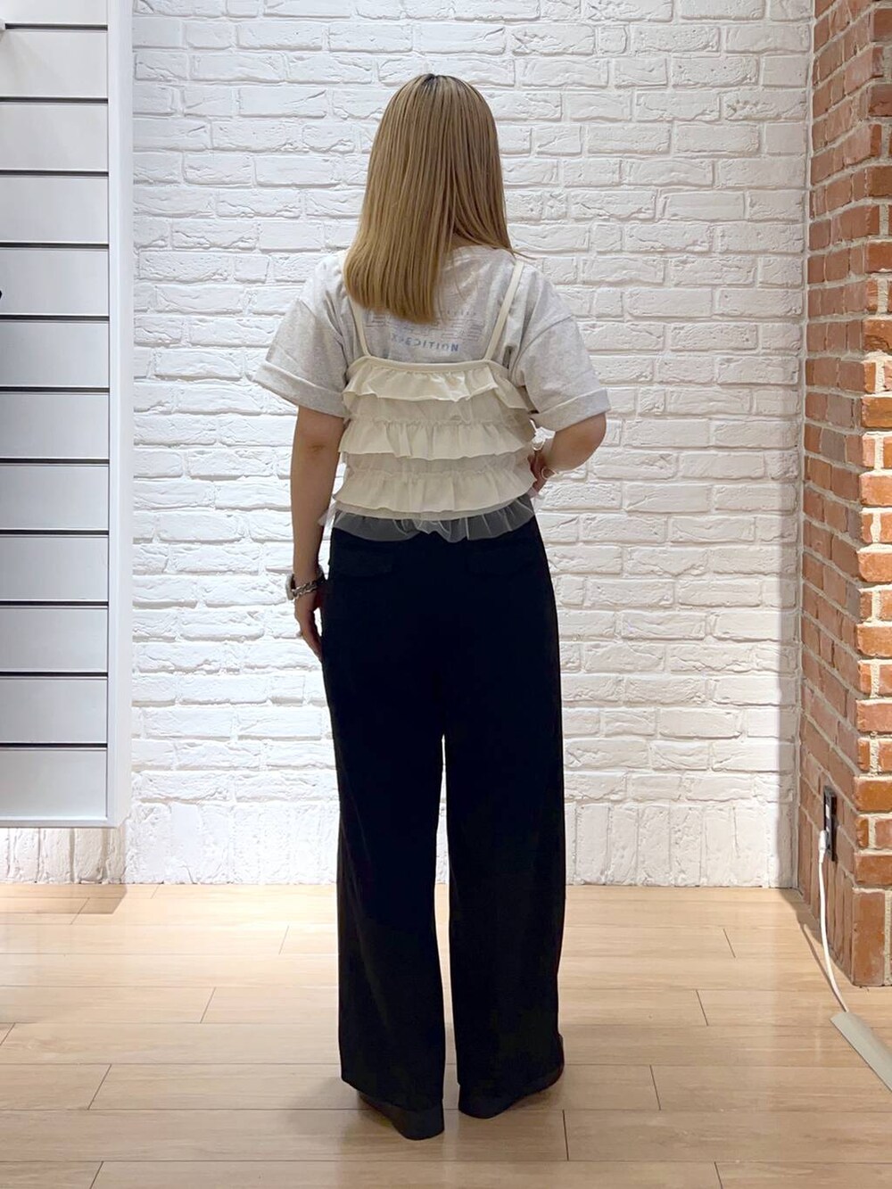 ブラック系のサンダル、ホワイト系のキャミソール、ブラック系のスラックスを着用したレディースの夏コーディネートの3枚目の写真