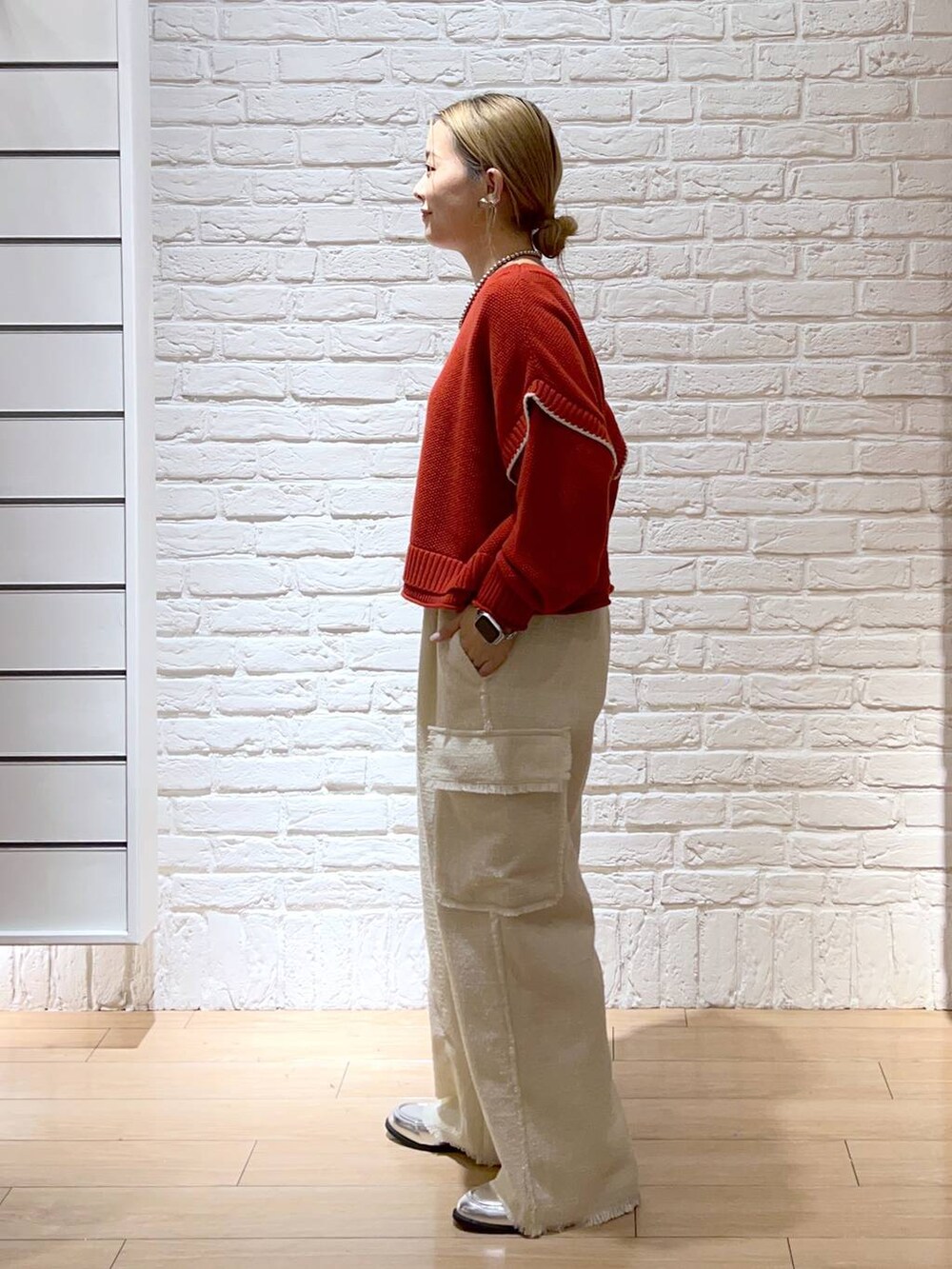 レッド系のニット/セーター、シルバー系のローファー、ホワイト系のその他パンツを着用したレディースの秋コーディネートの3枚目の写真