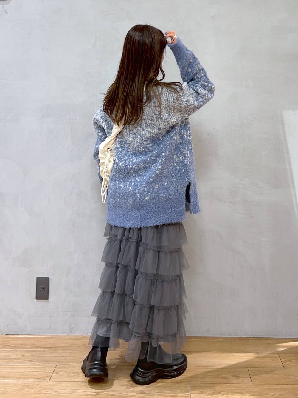 ホワイト系のショルダーバッグ、ブルー系のニット/セーター、グレー系のスカートを着用したレディースの秋コーディネートの5枚目の写真