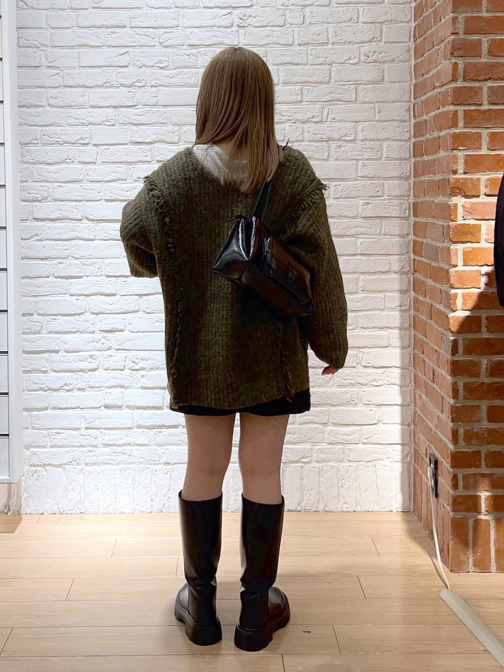 グリーン系のニット/セーター、シルバー系のTシャツ/カットソー、ブラック系のショルダーバッグを着用したレディースの秋コーディネートの4枚目の写真