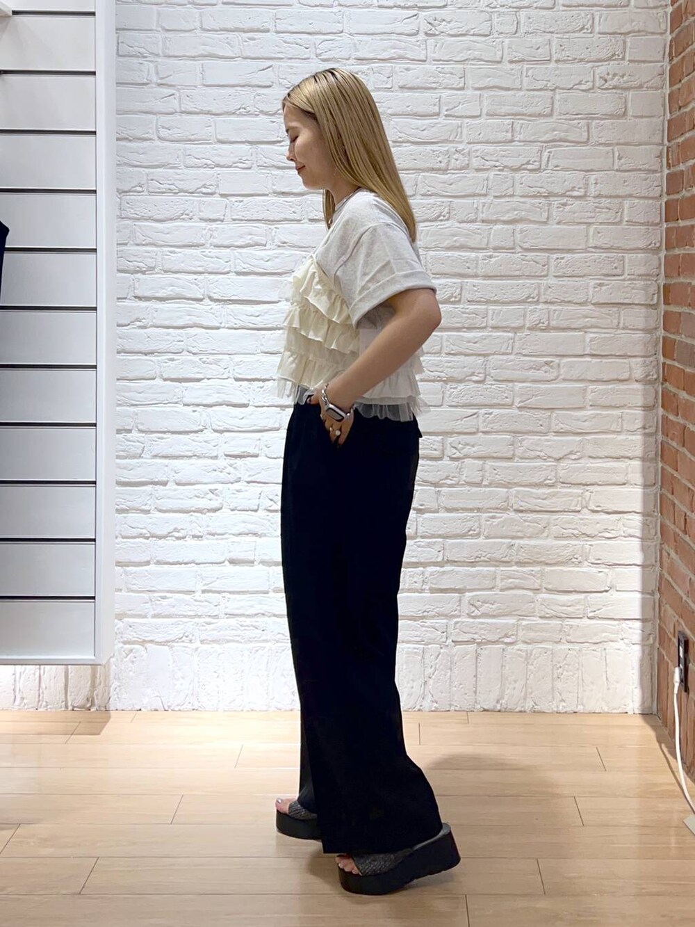 ブラック系のサンダル、ホワイト系のキャミソール、ブラック系のスラックスを着用したレディースの夏コーディネートの2枚目の写真