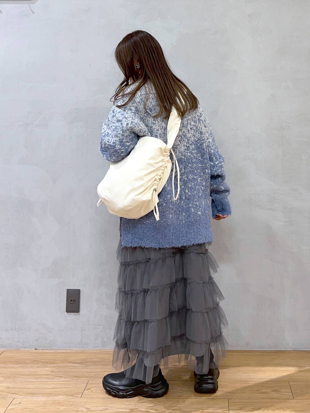 ホワイト系のショルダーバッグ、ブルー系のニット/セーター、グレー系のスカートを着用したレディースの秋コーディネートの4枚目の写真