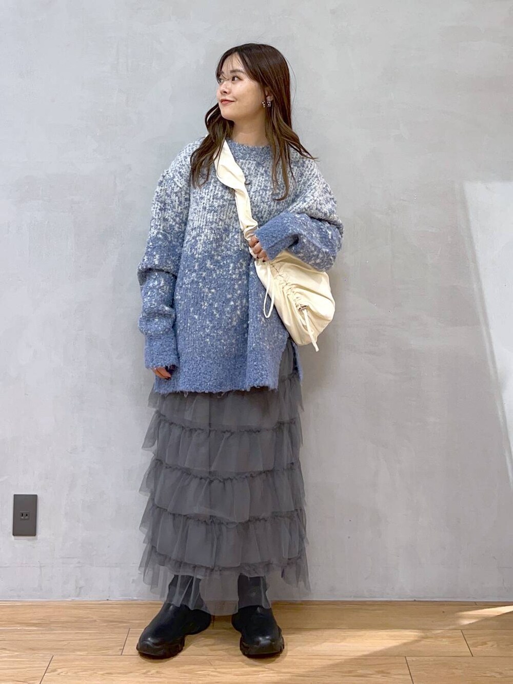 ホワイト系のショルダーバッグ、ブルー系のニット/セーター、グレー系のスカートを着用したレディースの秋コーディネートの2枚目の写真