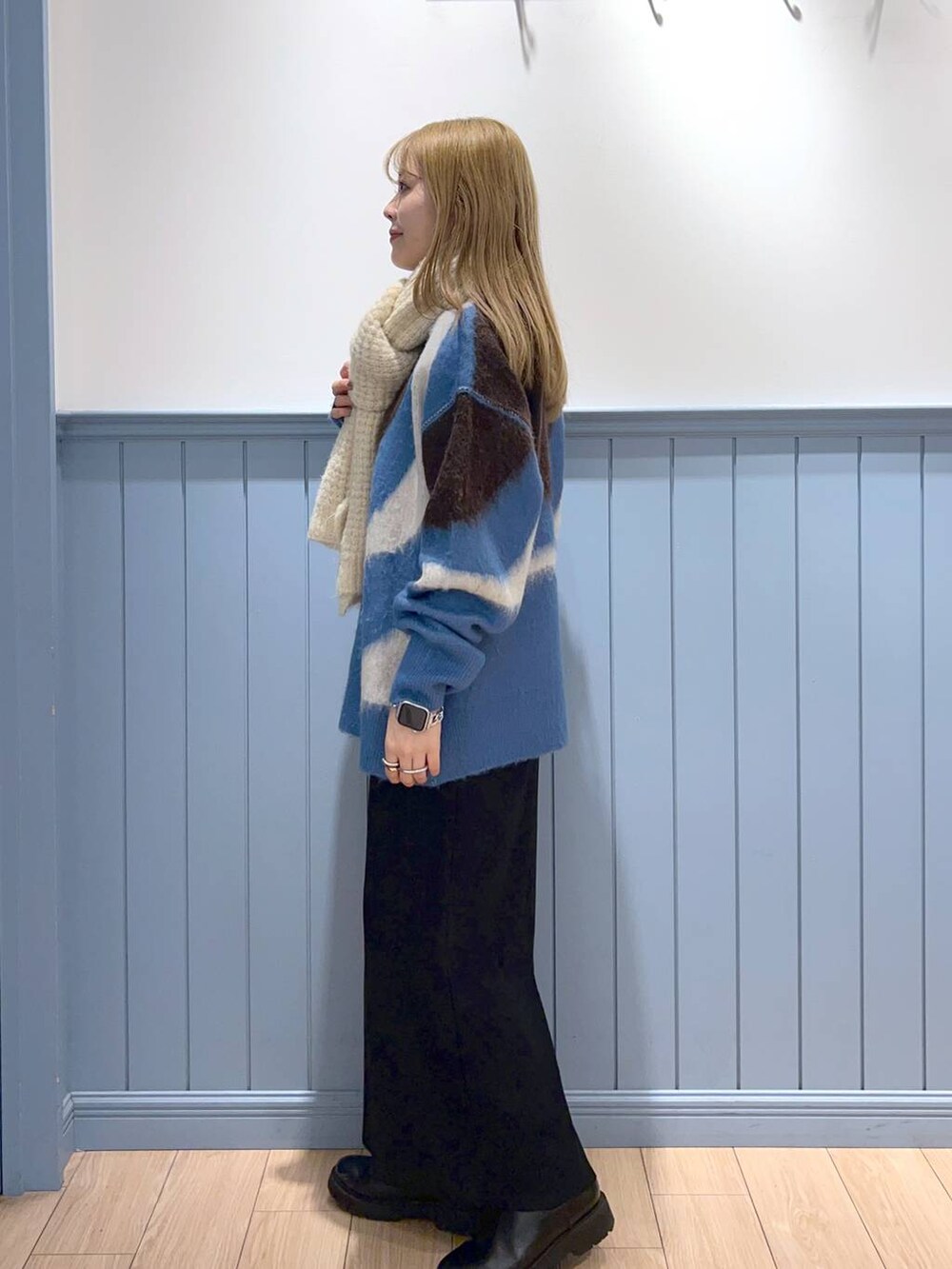 ブラック系のスカート、ブルー系のニット/セーター、ブラック系のブーツを着用したレディースの冬コーディネートの3枚目の写真