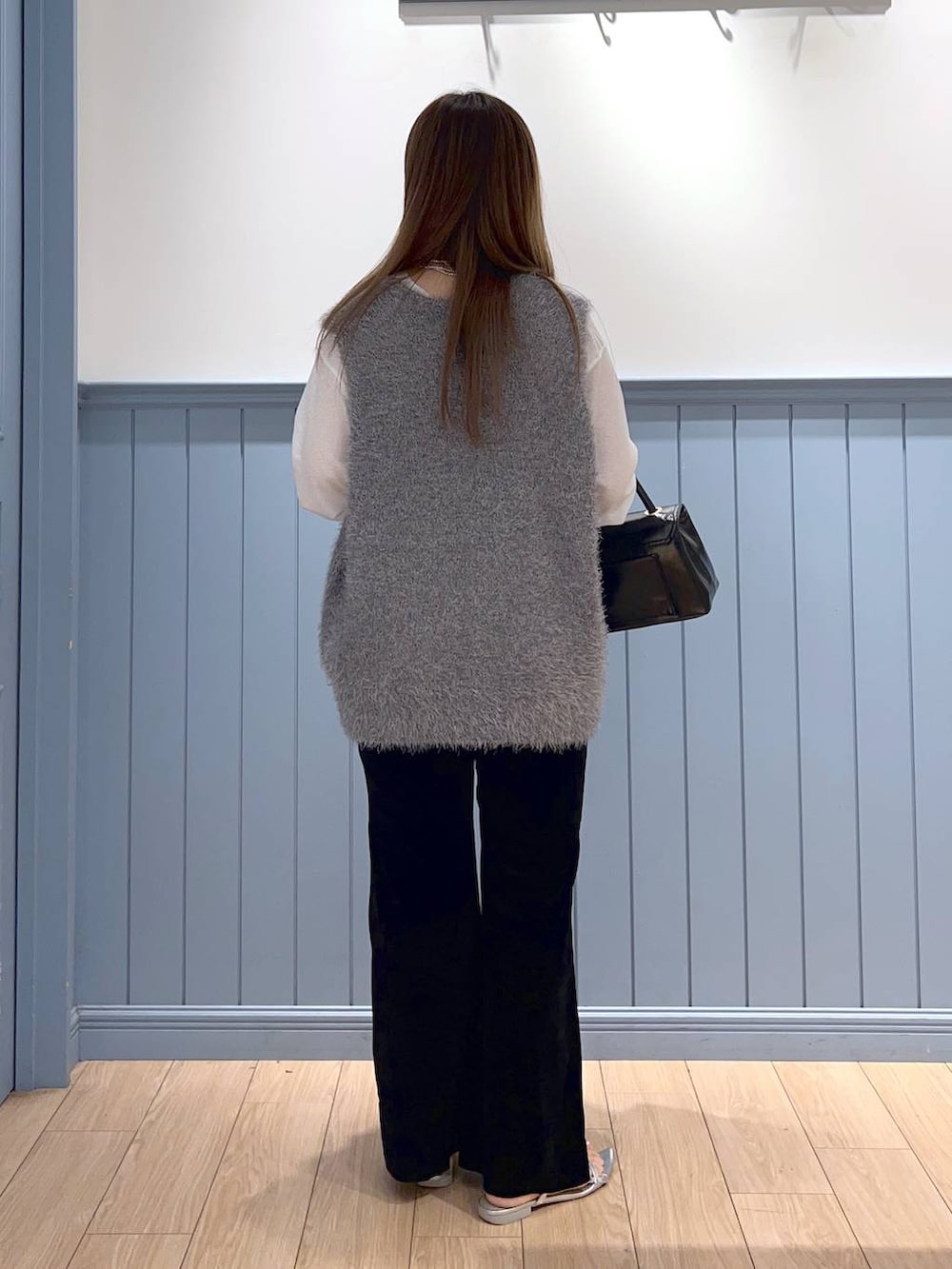 シルバー系のサンダル、ブラック系のボストンバッグ、グレー系のベストを着用したレディースの秋コーディネートの3枚目の写真