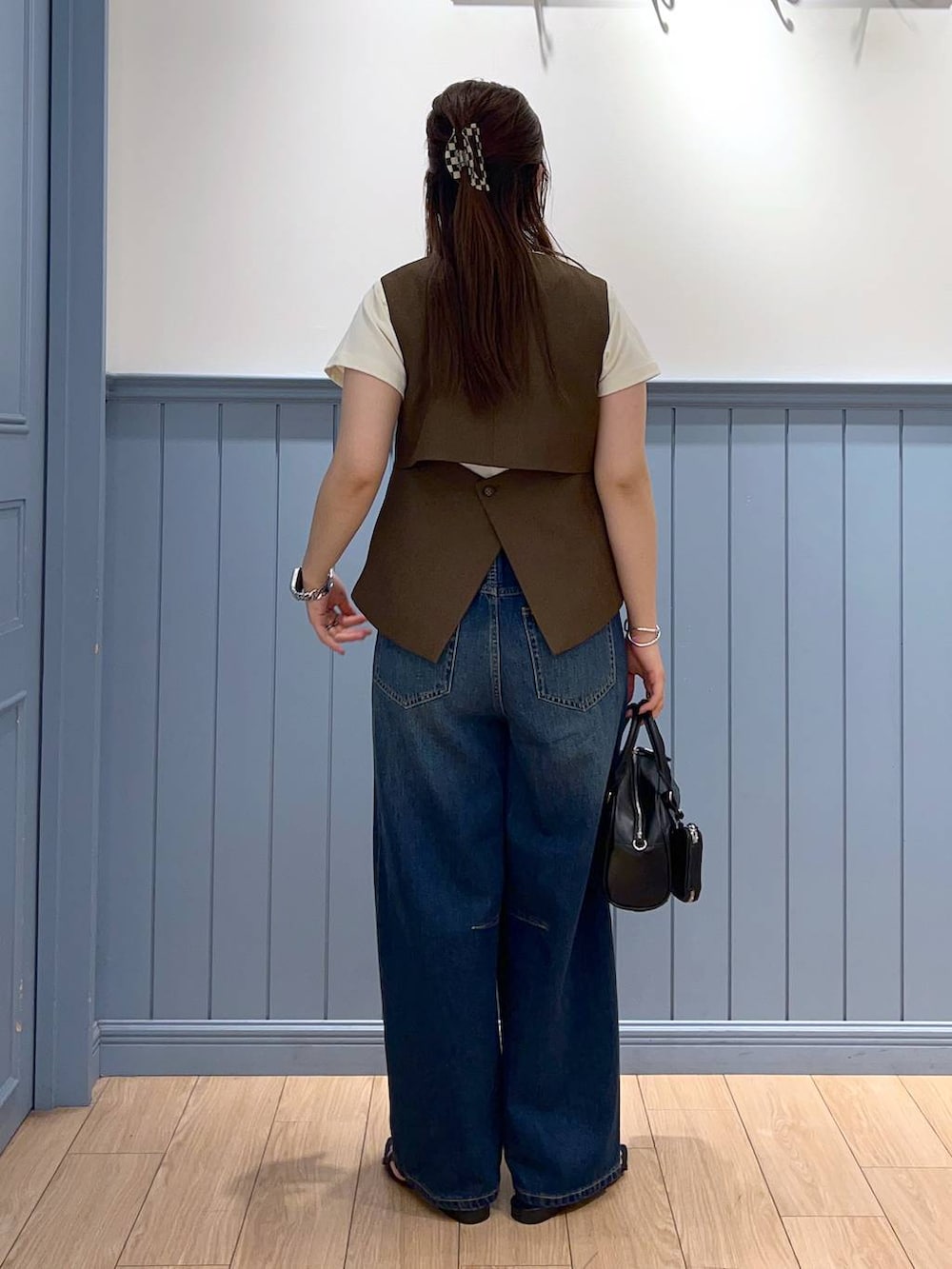 ブラック系のサンダル、ブルー系のデニムパンツ、ブラック系のショルダーバッグを着用したレディースの夏コーディネートの3枚目の写真