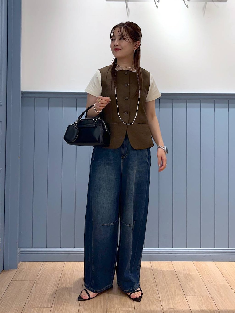 ブラック系のサンダル、ブルー系のデニムパンツ、ブラック系のショルダーバッグを着用したレディースの夏コーディネートの2枚目の写真