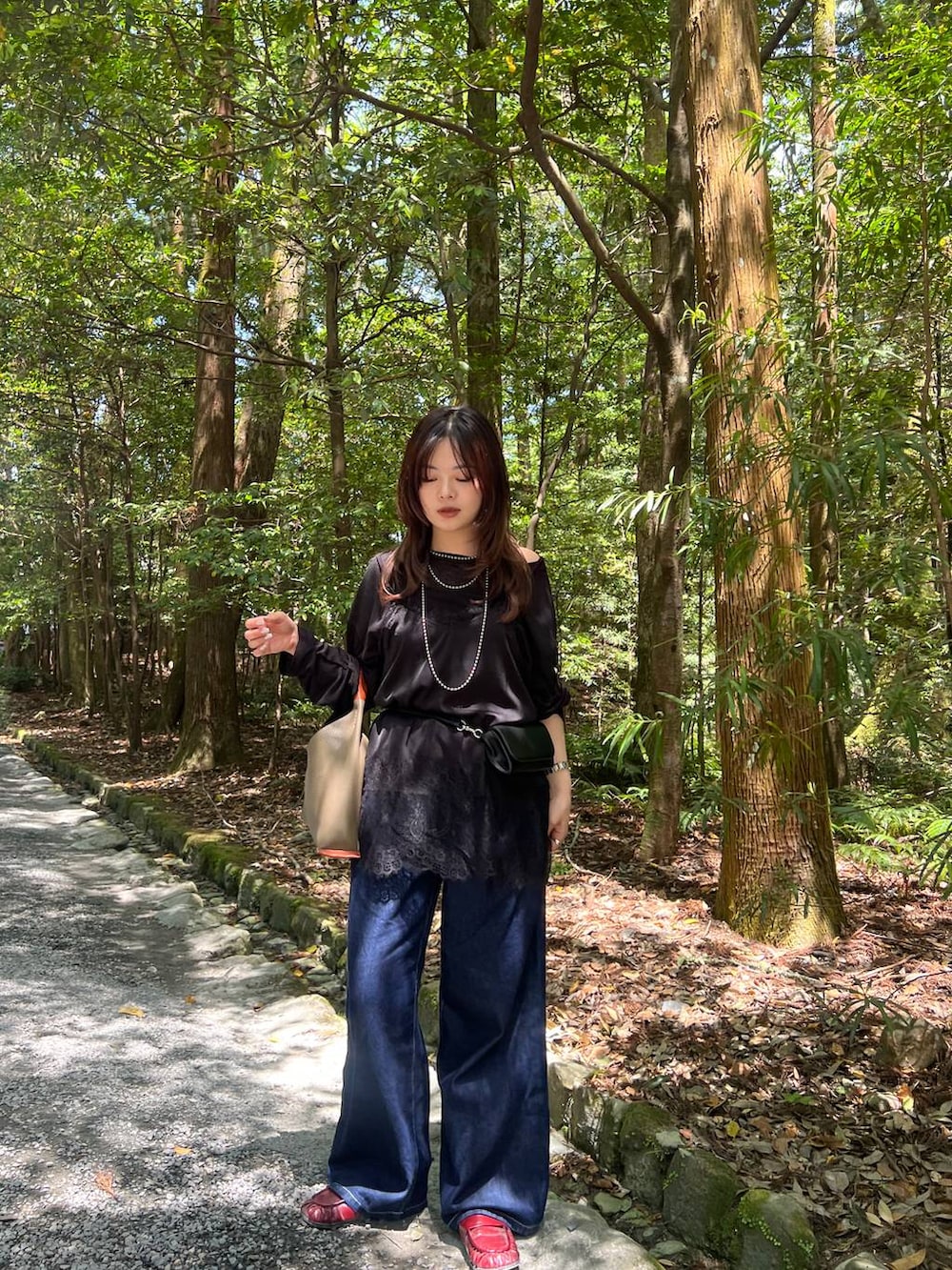 ブラック系のTシャツ/カットソー、ブラック系のボディバッグ/ウエストポーチ、ブルー系のデニムパンツを着用したレディースの春コーディネートの3枚目の写真