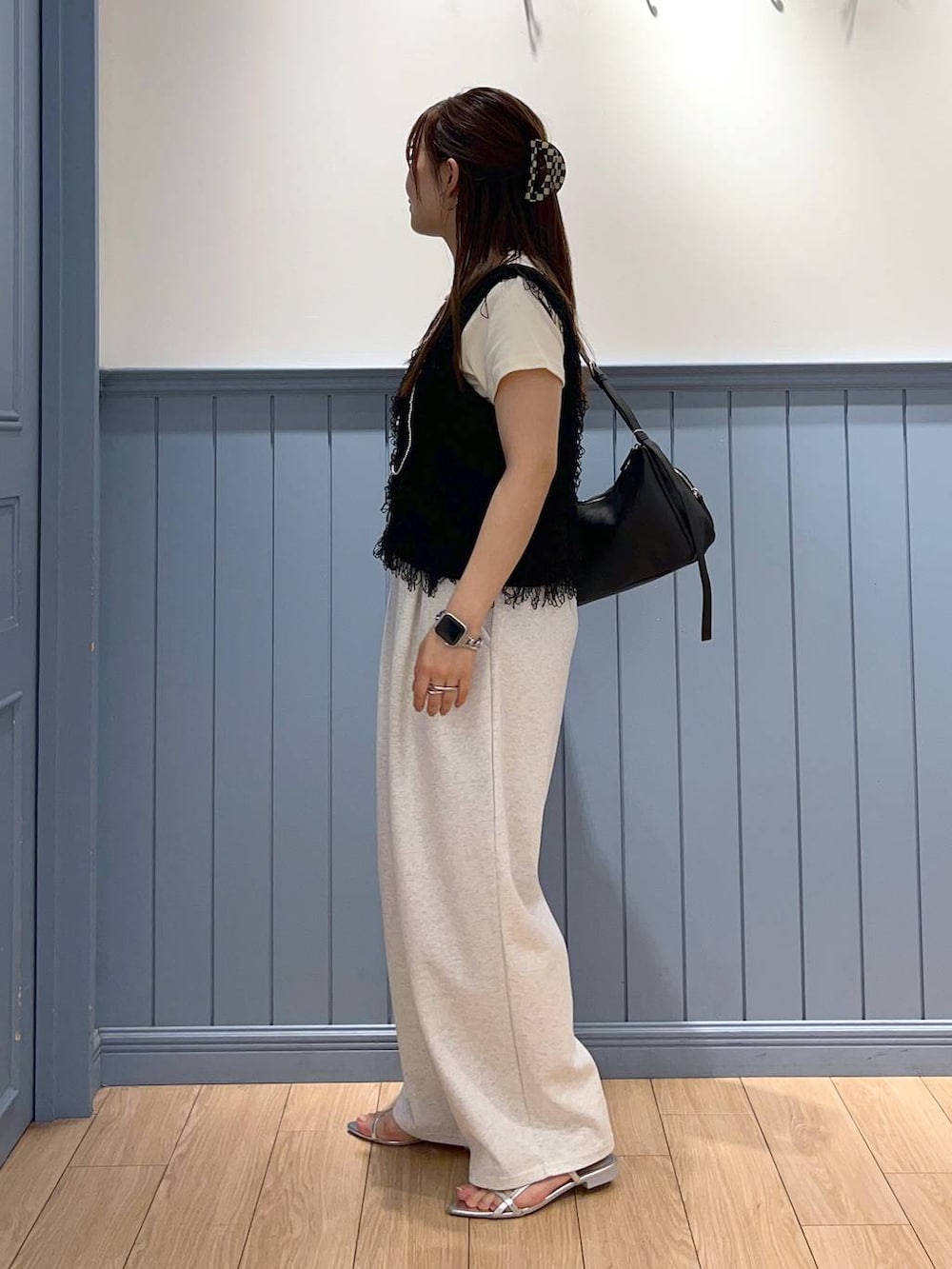 シルバー系のサンダル、グレー系のデニムパンツ、ブラック系のショルダーバッグを着用したレディースの夏コーディネートの3枚目の写真