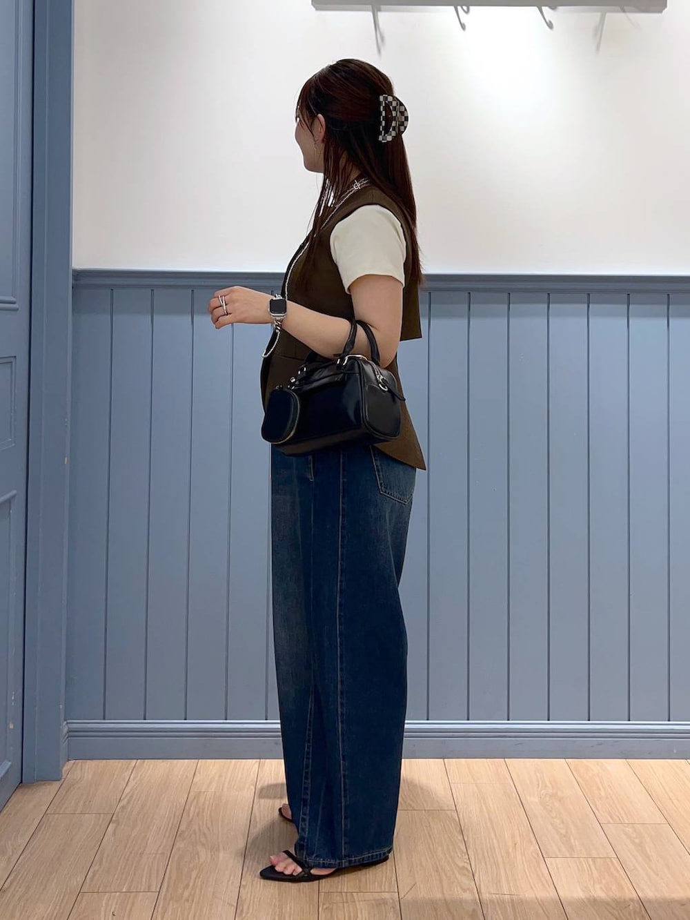 ブラック系のサンダル、ブルー系のデニムパンツ、ブラック系のショルダーバッグを着用したレディースの夏コーディネートの4枚目の写真