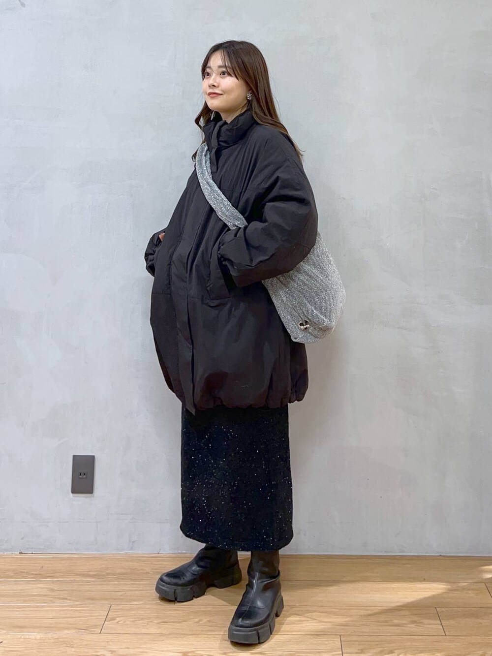 ブラック系のダウンジャケット/コート、シルバー系のショルダーバッグ、ブラック系のブーツを着用したレディースの秋コーディネートの2枚目の写真