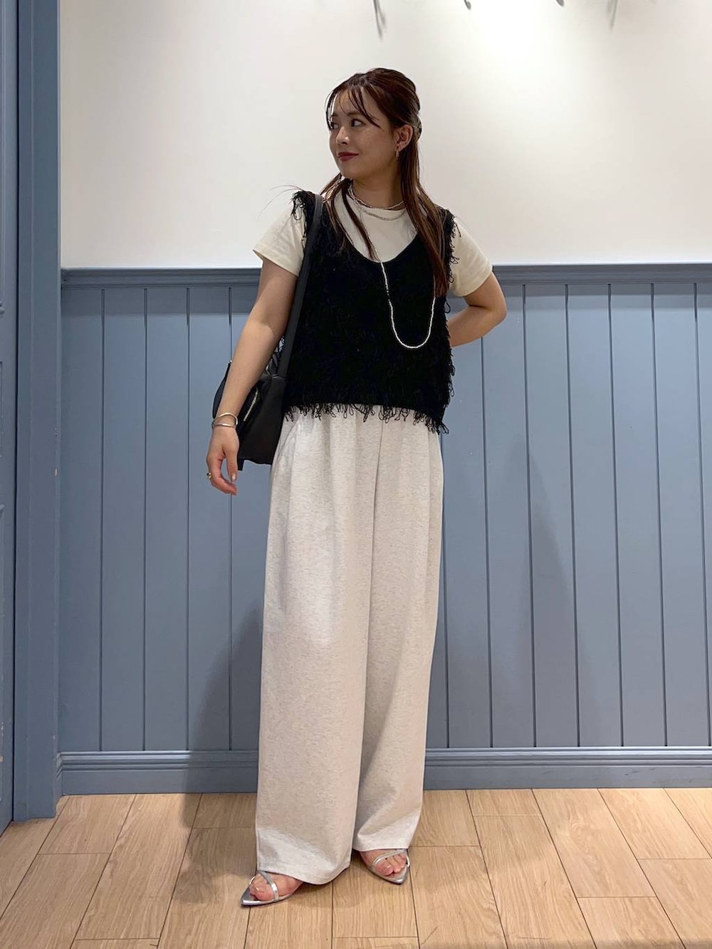 シルバー系のサンダル、グレー系のデニムパンツ、ブラック系のショルダーバッグを着用したレディースの夏コーディネートの2枚目の写真