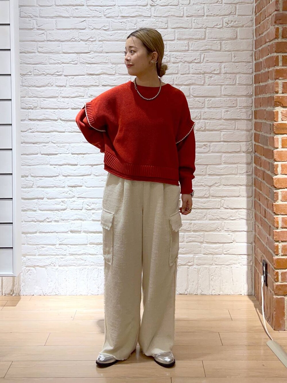 レッド系のニット/セーター、シルバー系のローファー、ホワイト系のその他パンツを着用したレディースの秋コーディネートの2枚目の写真