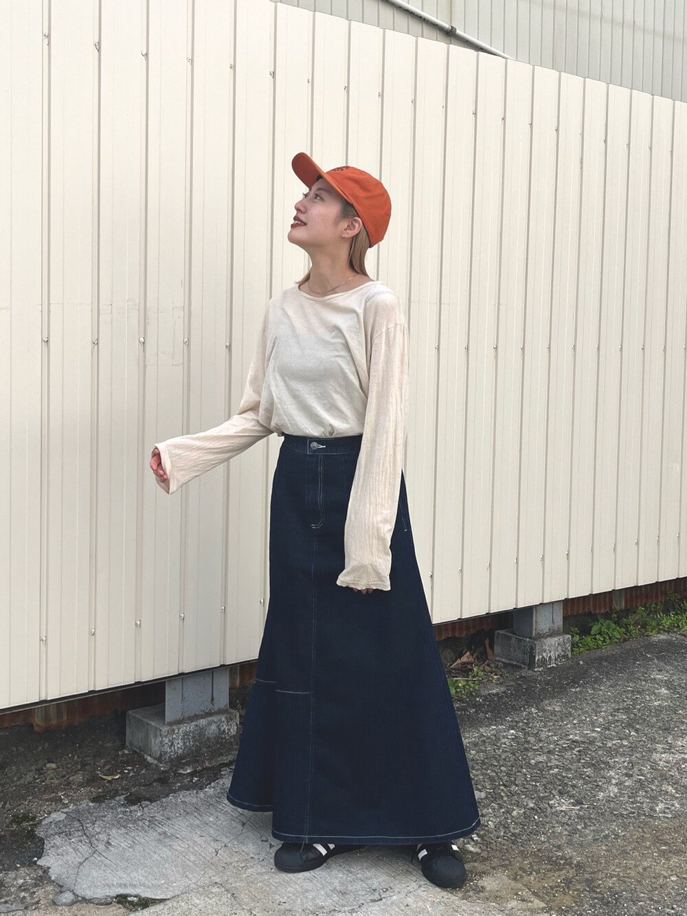 ブラック系のスニーカー、ブルー系のスカート、ホワイト系のTシャツ/カットソーを着用したレディースの春コーディネートの2枚目の写真