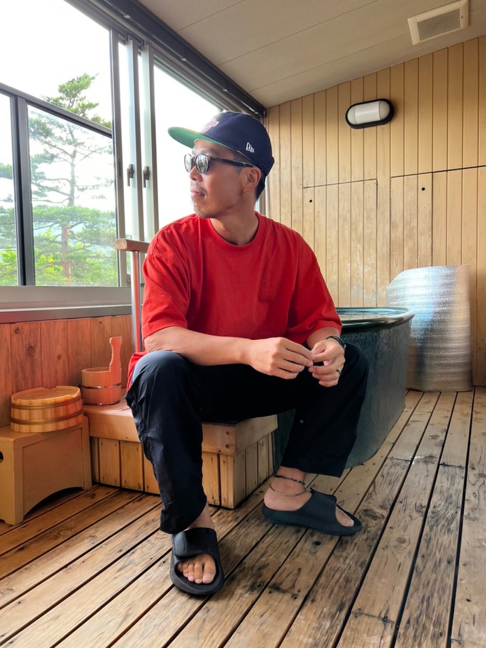 オレンジ系のTシャツ/カットソー、ブラック系のその他パンツ、ブラック系のサンダルを着用したメンズの夏コーディネートの2枚目の写真