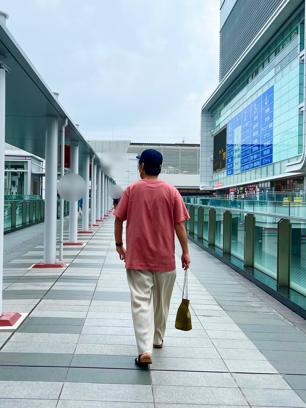 レッド系のTシャツ/カットソー、ベージュ系のパンツ、グリーン系のショルダーバッグを着用したメンズの夏コーディネートの3枚目の写真