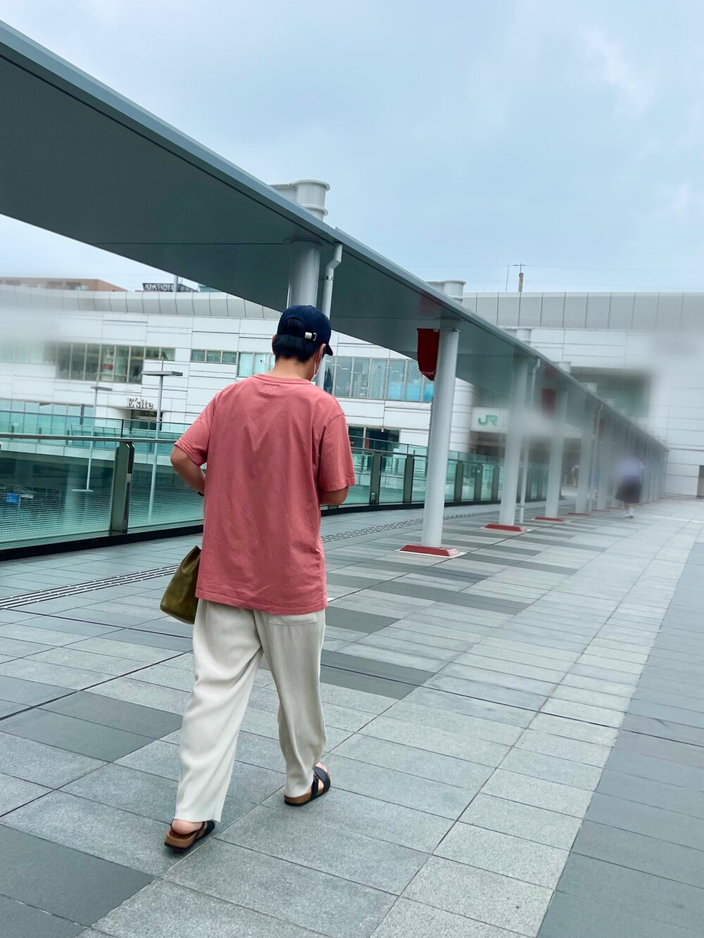 レッド系のTシャツ/カットソー、ベージュ系のパンツ、グリーン系のショルダーバッグを着用したメンズの夏コーディネートの2枚目の写真