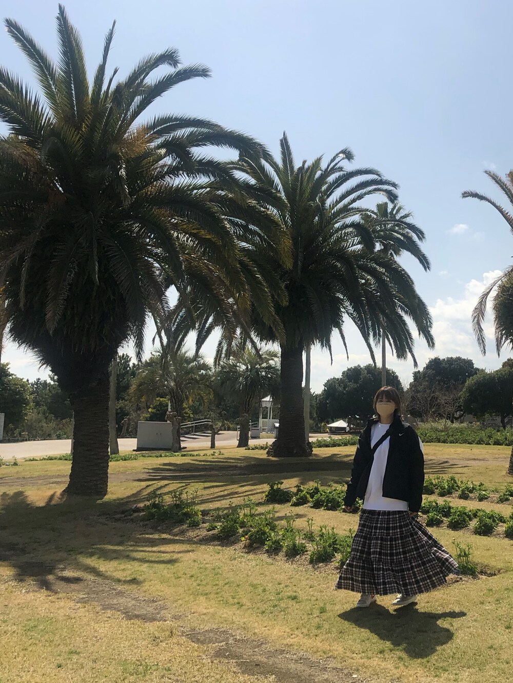 ブラック系のボディバッグ/ウエストポーチ、ブラウン系のスカート、ベージュ系のスニーカーを着用したレディースの春コーディネートの2枚目の写真