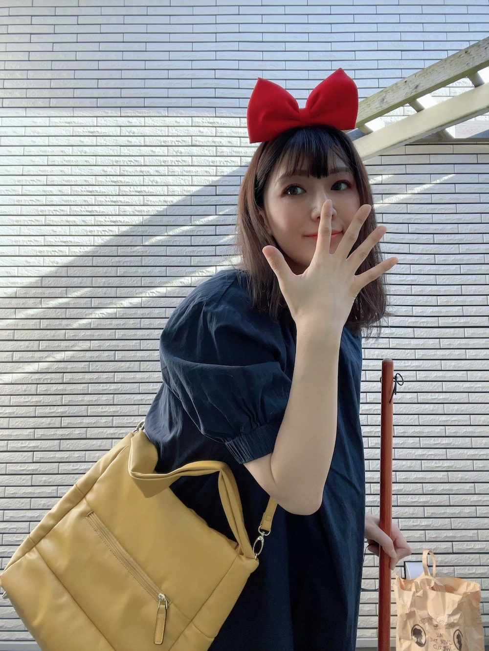 イエロー系のトートバッグ、ブルー系のワンピース、ブラック系のブーツを着用したレディースの秋コーディネートの2枚目の写真