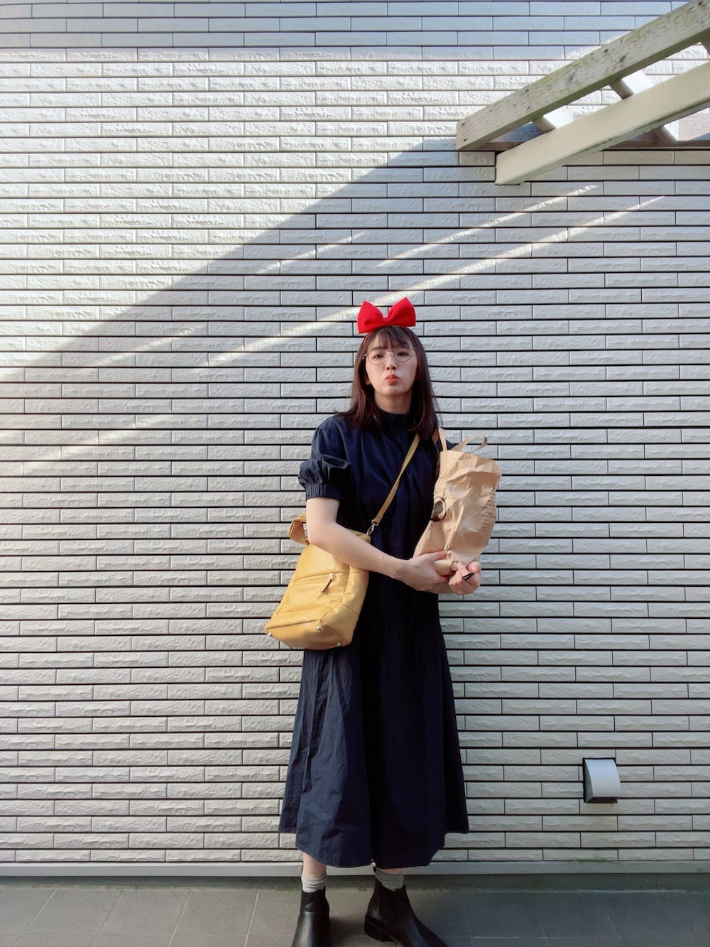イエロー系のトートバッグ、ブルー系のワンピース、ブラック系のブーツを着用したレディースの秋コーディネートの3枚目の写真